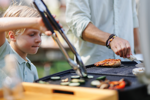 Child grilling with his dad