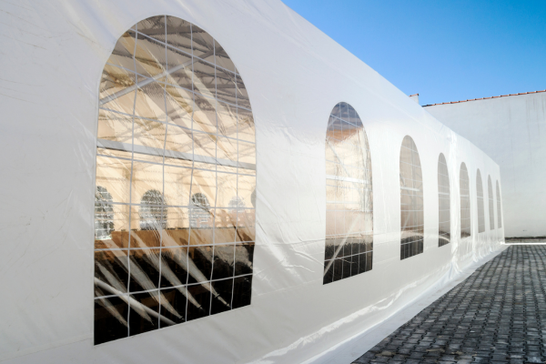 The side of a white party tent outdoors on a  clear day