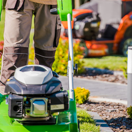 Landscaping RentalsLandscaper with push mower and a riding mower in the background