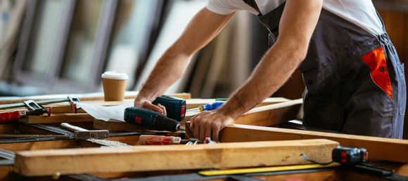 Carpenter using a power drill on wood project